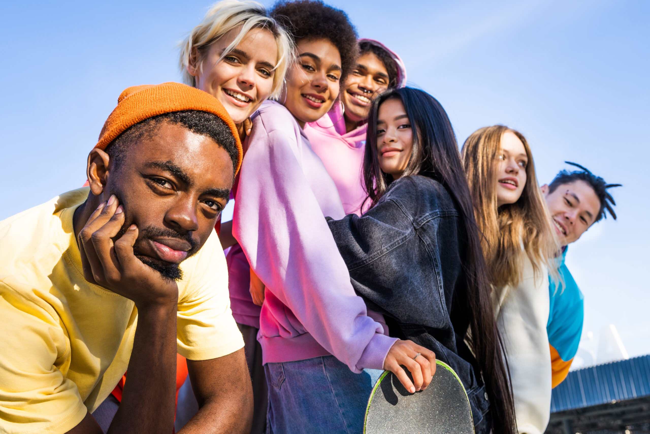 Multicultural group of young friends bonding outdoors and having fun - Stylish cool teens gathering at urban skate park